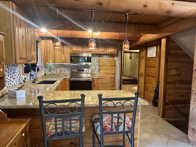 kitchen with kitchen peninsula, appliances with stainless steel finishes, pendant lighting, and sink