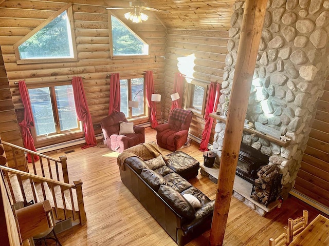 living area featuring rustic walls, ceiling fan, a stone fireplace, high vaulted ceiling, and wood-type flooring