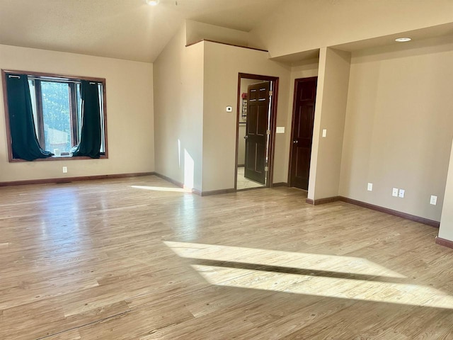 spare room with light hardwood / wood-style flooring and vaulted ceiling