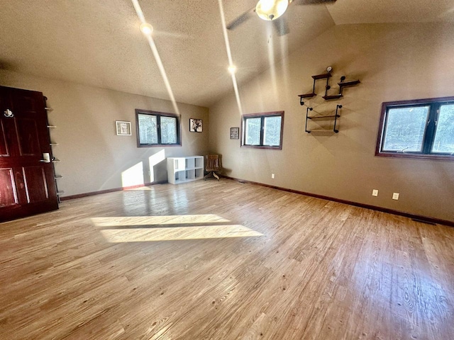 interior space with a textured ceiling, ceiling fan, light hardwood / wood-style floors, and lofted ceiling