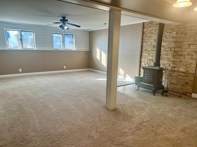 unfurnished living room with light colored carpet, a wood stove, ceiling fan, and ornamental molding