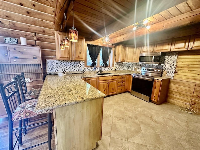 kitchen with kitchen peninsula, appliances with stainless steel finishes, sink, log walls, and a breakfast bar area