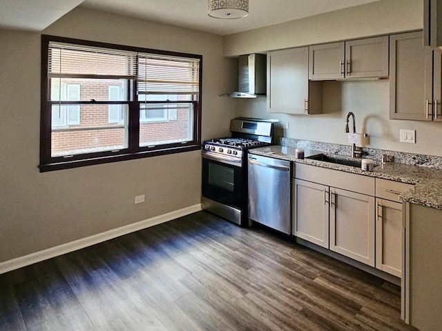 kitchen featuring sink, dark wood-type flooring, wall chimney range hood, light stone counters, and appliances with stainless steel finishes