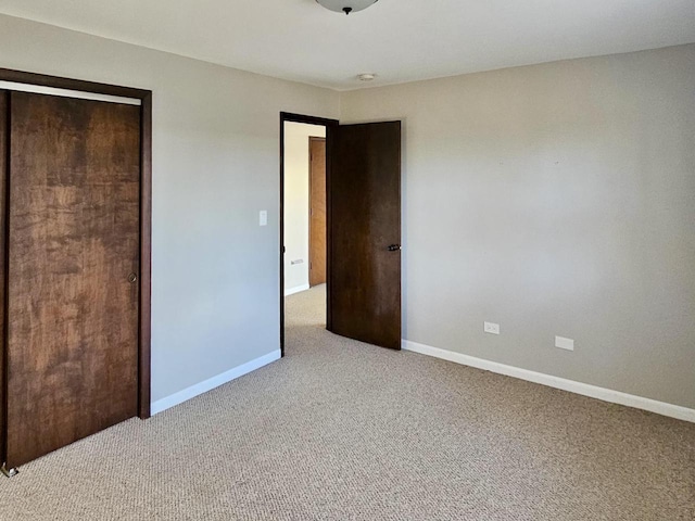 unfurnished bedroom featuring a closet and light colored carpet