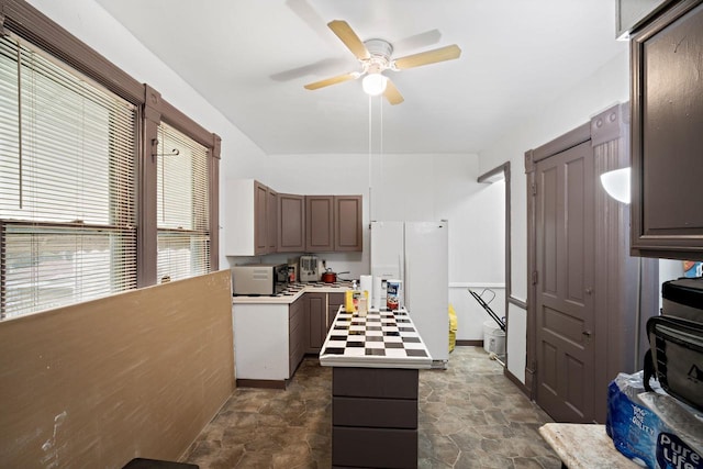 kitchen with a center island, dark brown cabinets, ceiling fan, and white appliances