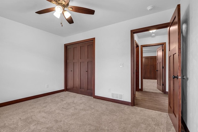 unfurnished bedroom featuring ceiling fan, light carpet, and a closet