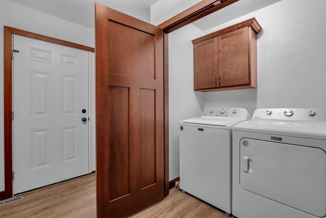 clothes washing area with cabinets, independent washer and dryer, and light hardwood / wood-style floors