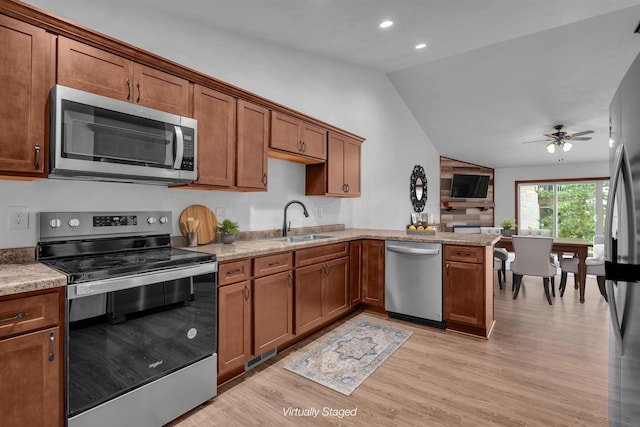 kitchen featuring light wood-type flooring, stainless steel appliances, ceiling fan, sink, and lofted ceiling