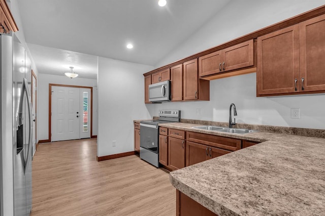 kitchen with sink, stainless steel appliances, vaulted ceiling, and light hardwood / wood-style floors