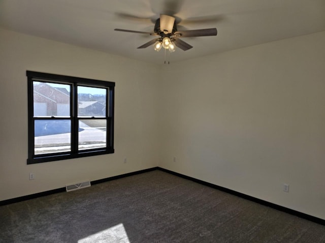 empty room featuring dark carpet and ceiling fan