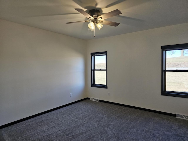 empty room featuring ceiling fan and dark colored carpet