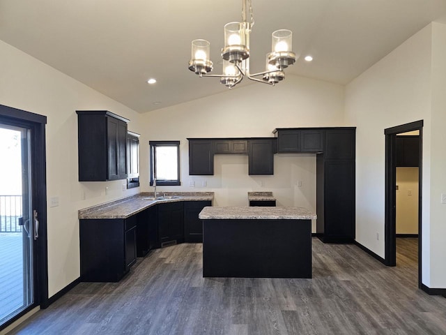 kitchen featuring dark hardwood / wood-style flooring, vaulted ceiling, sink, an inviting chandelier, and a kitchen island