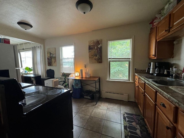 kitchen with stove, a baseboard heating unit, sink, a textured ceiling, and white fridge