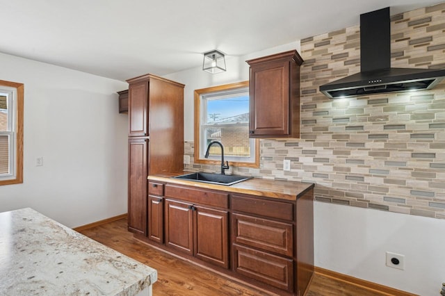 kitchen with decorative backsplash, hardwood / wood-style floors, wall chimney exhaust hood, and sink