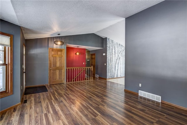 unfurnished room featuring a textured ceiling, dark wood-type flooring, and vaulted ceiling