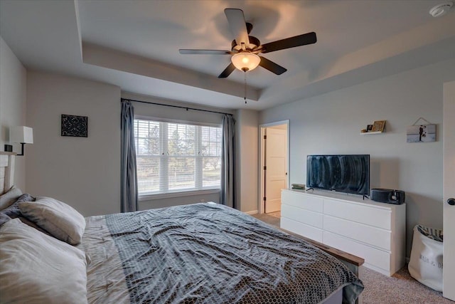 bedroom with a tray ceiling, ceiling fan, and light carpet