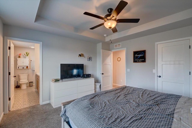 carpeted bedroom featuring ceiling fan, connected bathroom, and a tray ceiling