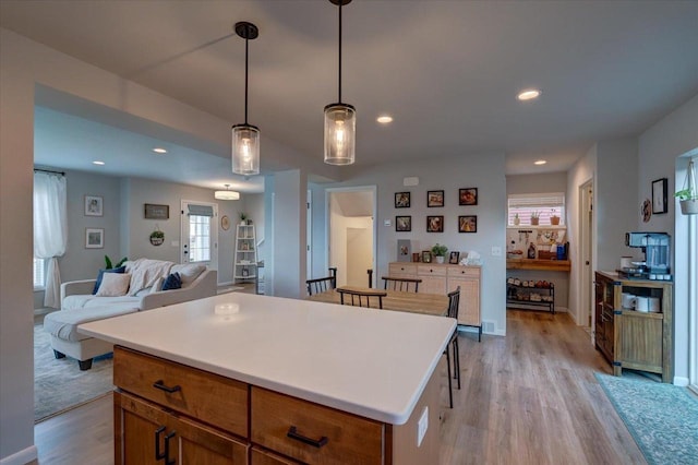 kitchen featuring pendant lighting, a center island, a kitchen bar, and light wood-type flooring