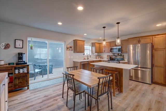 kitchen featuring sink, hanging light fixtures, light hardwood / wood-style flooring, a kitchen island, and stainless steel appliances