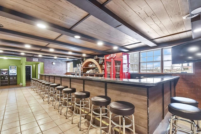 bar featuring beam ceiling, light tile patterned floors, wooden ceiling, and brick wall