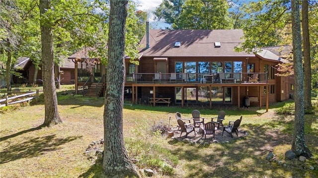 rear view of property featuring a yard, a fire pit, and a deck