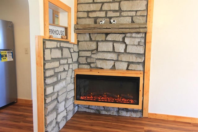 interior details featuring stainless steel fridge, a fireplace, and hardwood / wood-style flooring