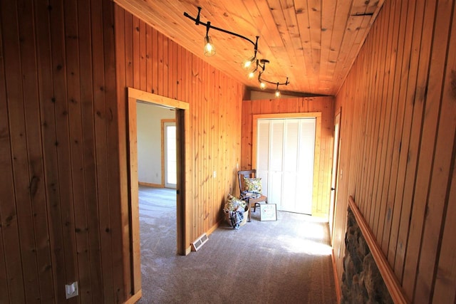 corridor with carpet floors, wooden ceiling, lofted ceiling, and wood walls