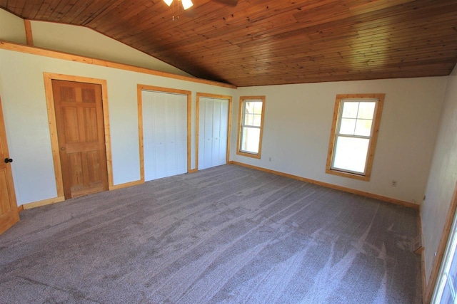 unfurnished bedroom featuring dark carpet, two closets, vaulted ceiling, and wooden ceiling