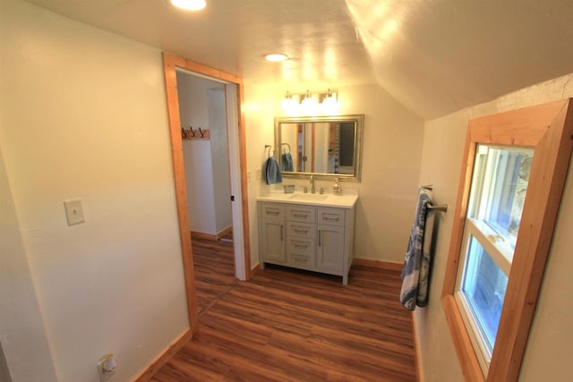 bathroom with hardwood / wood-style floors, vanity, and vaulted ceiling