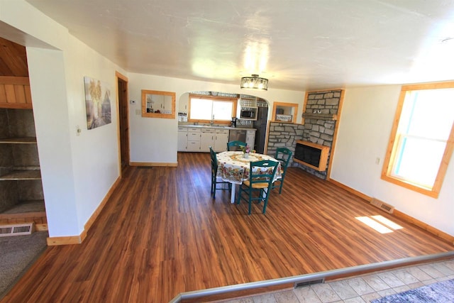 dining space with hardwood / wood-style floors, a stone fireplace, and sink