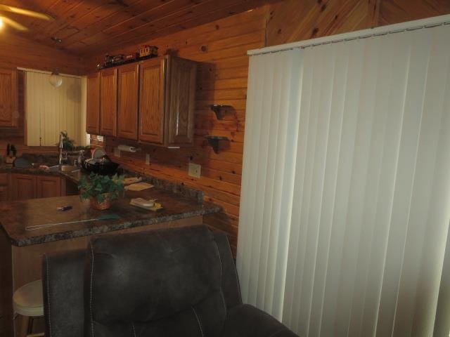 kitchen with kitchen peninsula, wooden walls, sink, and wooden ceiling