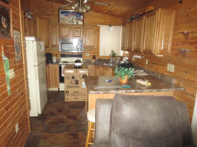 kitchen featuring wood walls, white refrigerator, ceiling fan, range, and wood ceiling