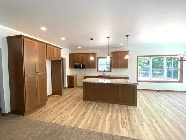 kitchen with decorative light fixtures, a center island, decorative backsplash, and sink