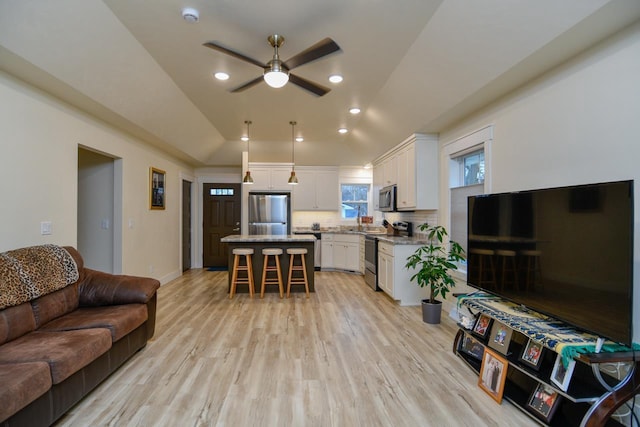 living room featuring ceiling fan, lofted ceiling, and light hardwood / wood-style flooring