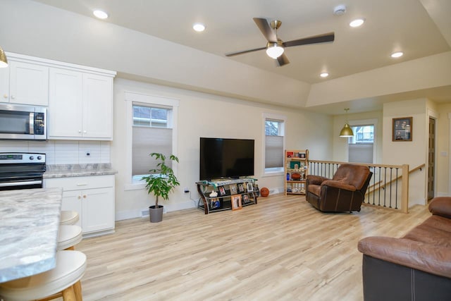 living room featuring a wealth of natural light, ceiling fan, and light wood-type flooring