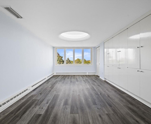 unfurnished room featuring dark hardwood / wood-style floors and a baseboard heating unit