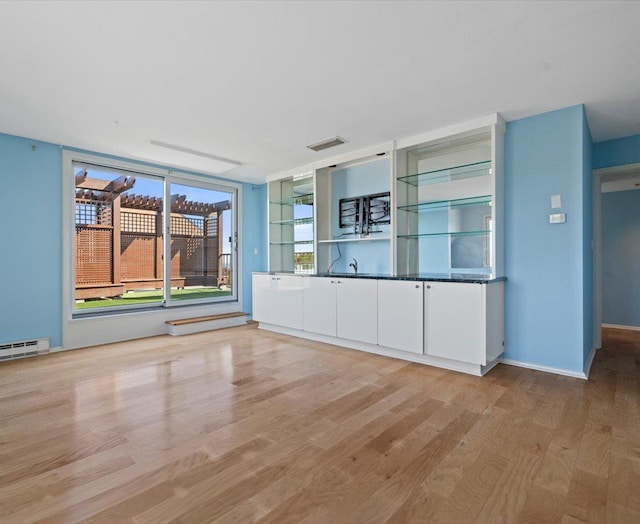 kitchen with white cabinets, light hardwood / wood-style flooring, and baseboard heating