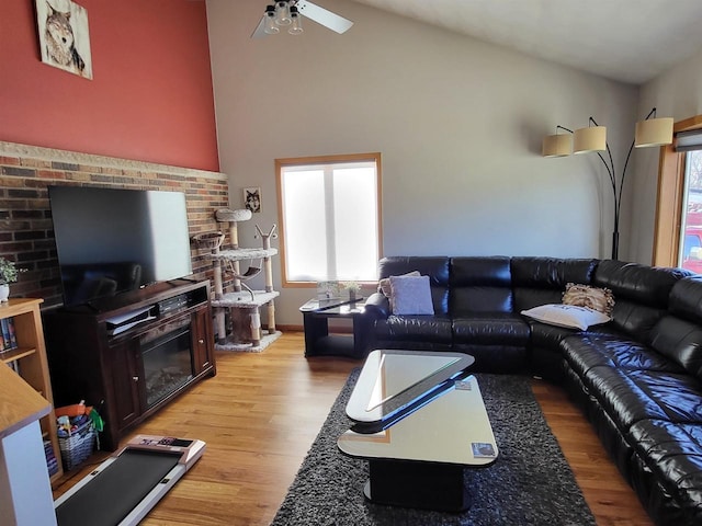 living room featuring ceiling fan, light hardwood / wood-style floors, lofted ceiling, and a fireplace