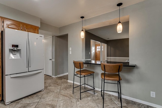 kitchen with decorative light fixtures, a kitchen bar, white refrigerator with ice dispenser, and kitchen peninsula