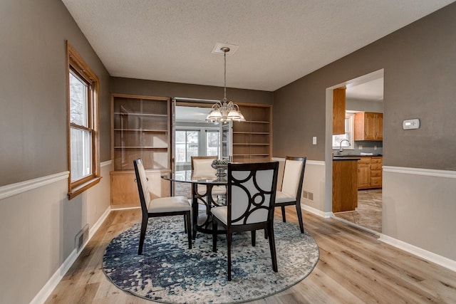 dining space featuring a chandelier, a textured ceiling, light hardwood / wood-style floors, and a wealth of natural light