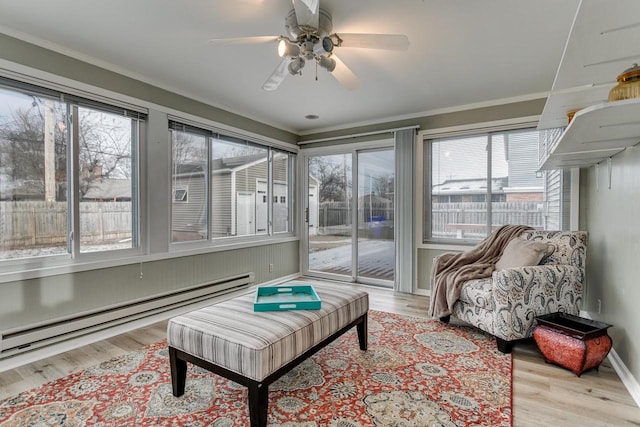 sunroom with plenty of natural light, a baseboard heating unit, and ceiling fan