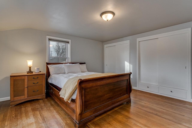 bedroom with light hardwood / wood-style flooring and multiple closets