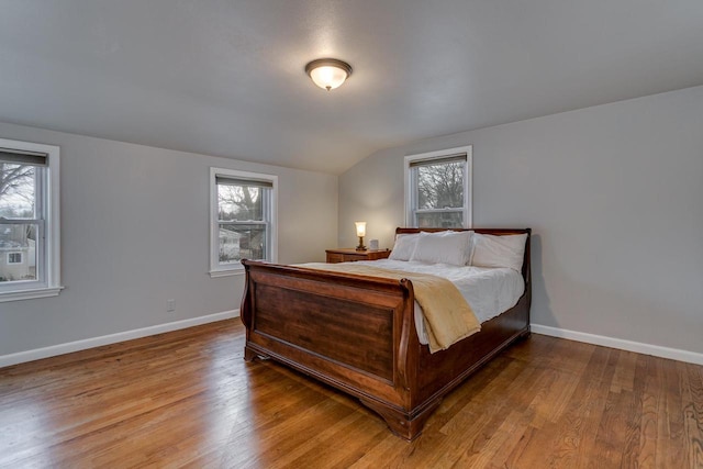 bedroom with light wood-type flooring, lofted ceiling, and multiple windows