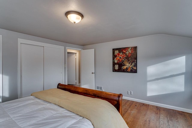 bedroom with a closet, wood-type flooring, and lofted ceiling