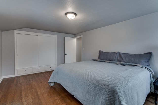 bedroom with dark hardwood / wood-style flooring, lofted ceiling, and a textured ceiling