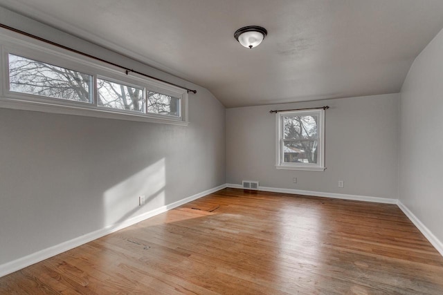 additional living space with light hardwood / wood-style flooring, a wealth of natural light, and lofted ceiling