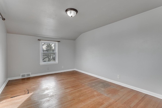 bonus room with light wood-type flooring and vaulted ceiling