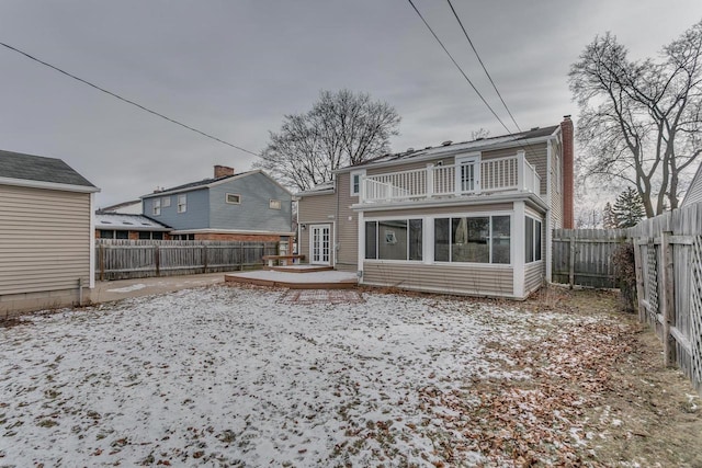 snow covered back of property with a balcony and a deck