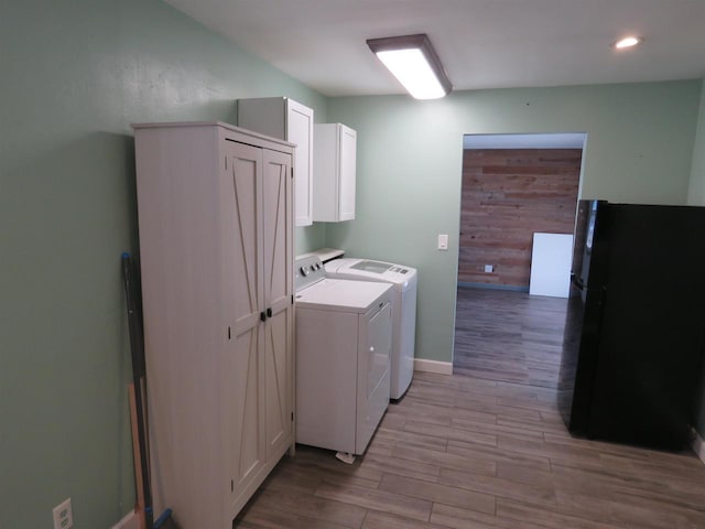 clothes washing area with washer and dryer and cabinets