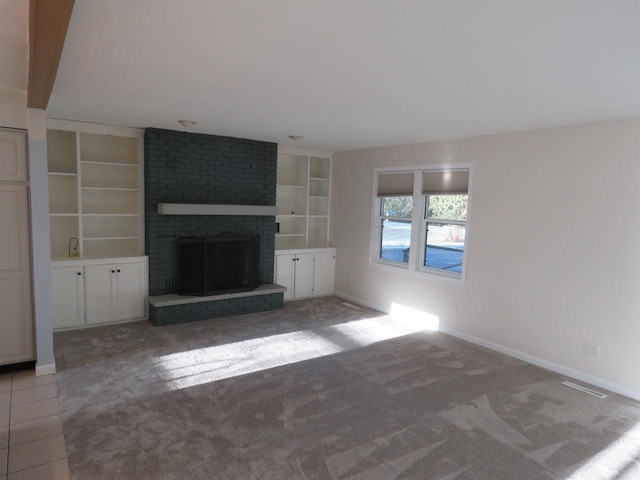 unfurnished living room with carpet, built in shelves, beam ceiling, and a fireplace